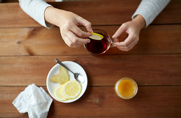 Image showing close up of woman adding lemon to tea cup