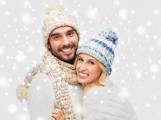 Image showing smiling couple in winter clothes hugging over snow