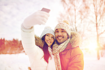 Image showing happy couple taking selfie by smartphone in winter