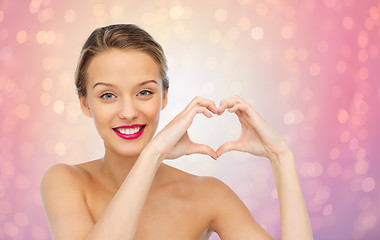 Image showing smiling young woman showing heart shape hand sign