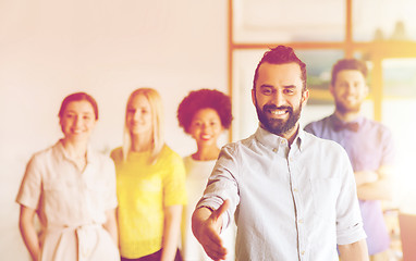 Image showing happy man making handshake over office team