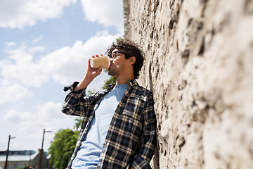 Image showing man in eyeglasses drinking coffee over street wall