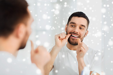 Image showing man with dental floss cleaning teeth at bathroom