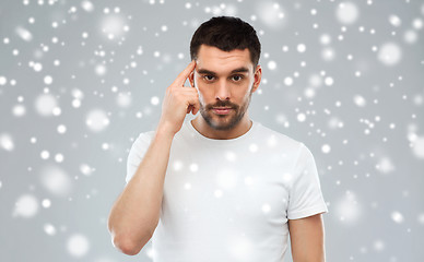 Image showing man with finger at temple over snow background