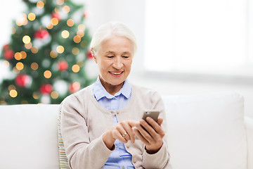 Image showing senior woman with smartphone texting at christmas