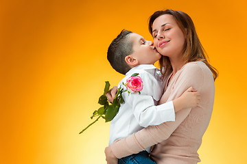 Image showing Young kid giving red rose to his mom