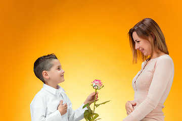 Image showing Young kid giving red rose to his mom