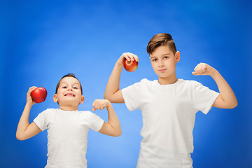 Image showing Handsome little boys with two red apples. Studio portrait over blue background