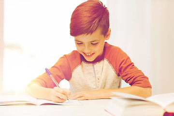 Image showing smiling student boy writing to notebook at home