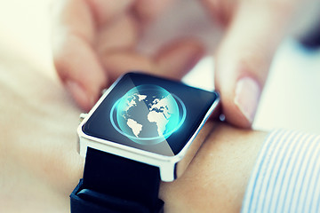 Image showing close up of hand with globe hologram on smartwatch