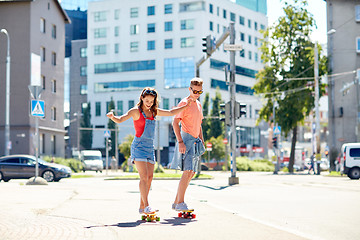 Image showing teenage couple riding skateboards on city street