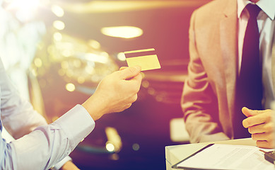 Image showing customer giving credit card to car dealer in salon