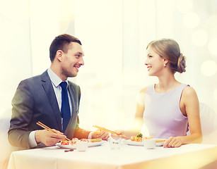 Image showing smiling couple eating sushi at restaurant