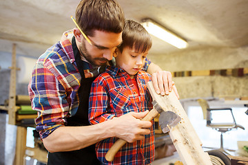 Image showing father and son with ax and wood plank at workshop