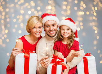 Image showing happy family holding gift boxes and sparkles