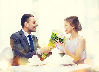 Image showing smiling man giving flower bouquet at restaurant