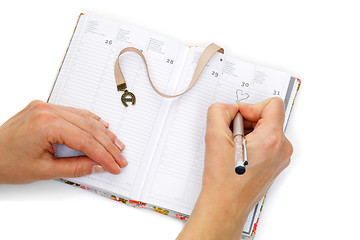 Image showing Notebook opened with female hands writing