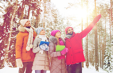 Image showing smiling friends with tablet pc in winter forest