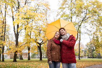 Image showing smiling couple with umbrella in autumn park