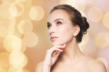 Image showing beautiful woman touching her face over lights