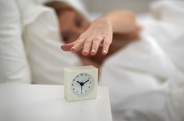 Image showing close up of woman with alarm clock in bed at home