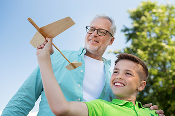 Image showing senior man and boy with toy airplane over sky