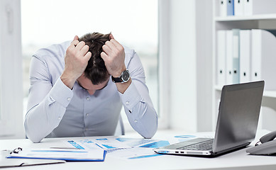 Image showing stressed businessman with papers in office