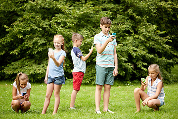 Image showing kids with smartphones playing game in summer park