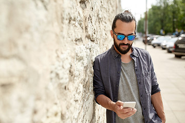 Image showing man texting message on smartphone at stone wall