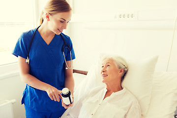 Image showing nurse giving medicine to senior woman at hospital