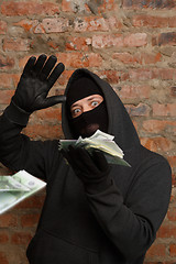 Image showing Robber in mask throws banknotes