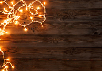 Image showing Christmas dark brown wooden background decorated with shining lights