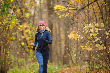 Image showing Young athletic woman running in autumn colorful forest