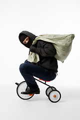 Image showing Thief in mask riding bicycle