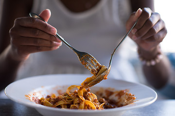 Image showing a young African American woman eating pasta