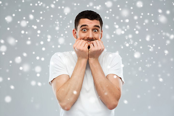 Image showing scared man in white t-shirt over snow background