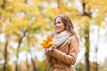 Image showing beautiful woman with maple leaves in autumn park