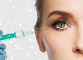 Image showing close up of woman face and syringe over snow