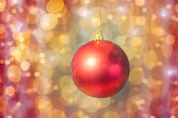 Image showing close up of red christmas ball over golden lights