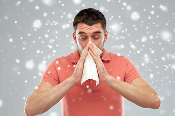 Image showing sick man with paper wipe blowing nose over snow