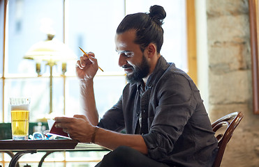 Image showing close up of man with beer and notebook at pub