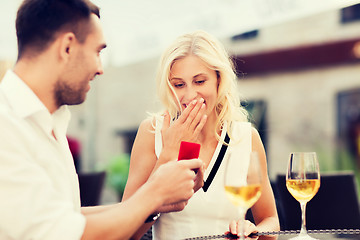 Image showing happy couple with engagement ring and wine at cafe