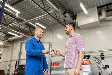 Image showing auto mechanic giving key to man at car shop