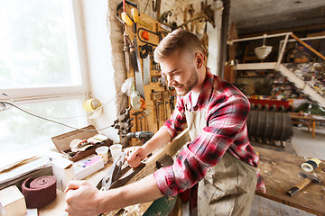 Image showing carpenter working with plane and wood at workshop