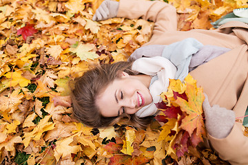 Image showing beautiful happy woman lying on autumn leaves