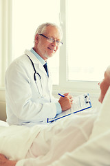 Image showing senior woman and doctor with clipboard at hospital