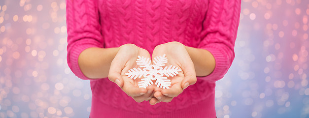 Image showing close up of woman in sweater holding snowflake