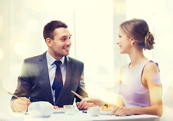 Image showing smiling couple eating sushi at restaurant