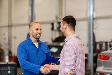 Image showing auto mechanic and man shaking hands at car shop