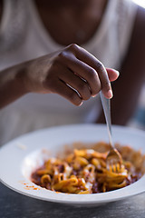 Image showing a young African American woman eating pasta